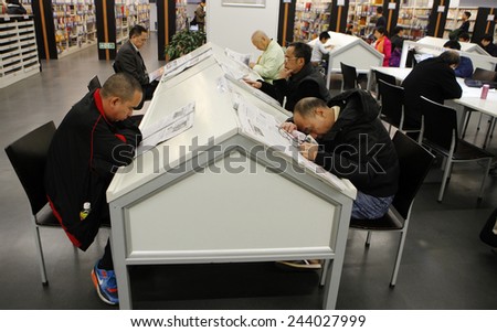 GUANGZHOU, CHINA - JAN. 14. 2015: A man sleeps on the table while others read around him in Guangzhou Library in Guangzhou, Guangdong province.