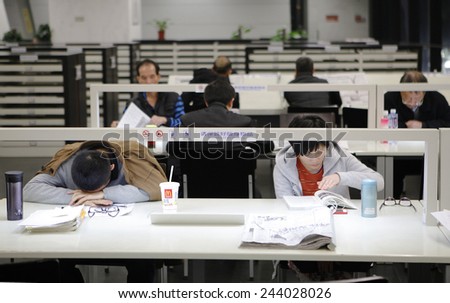 GUANGZHOU, CHINA - JAN. 14. 2015: A student sleeps on the table while others read around him in Guangzhou Library in Guangzhou, Guangdong province.