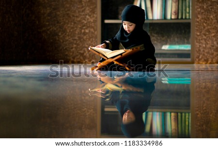 Asian Indonesian Muslim kid is reading the Quran. The Quran is indicated as the guided book for all Muslim and it is direction  to be on the heaven of God.Mosque,Islam,religion and knowledge concept.