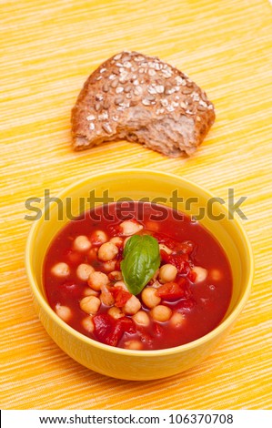 Bowl with soup of chick peas, tomatoes, basil and a roll
