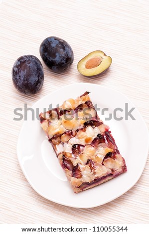 Plum cake on a plate with three plums