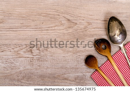 Wooden cooking spoon and silver spoon on a red napkin