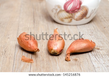 Three shallots on a old weathered wooden board
