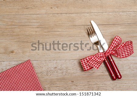 Table of wood with knife, fork and red checkered napkin