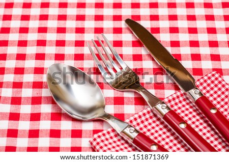 Red silverware on a red checkered napkin and table cloth