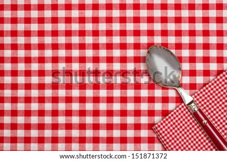 Spoon and napkin on a  checkered table cloth with red and white checks