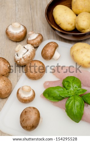 Raw turkey filet, mushrooms and potatoes in vertical format