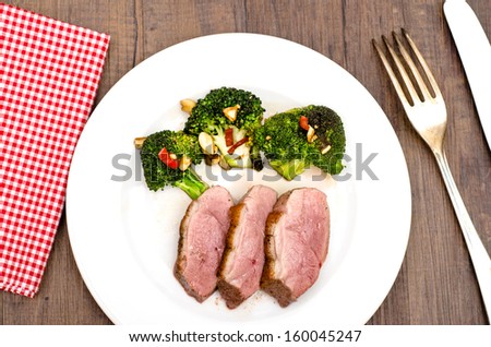 Roasted duck breast with green broccoli on a white plate