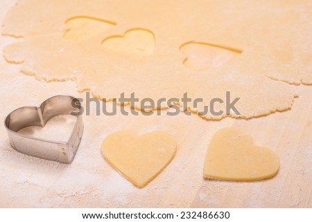 Cutter with heart shape of dough on flour