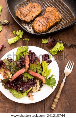 Entrecote in griddle pan and a plate with lettuce