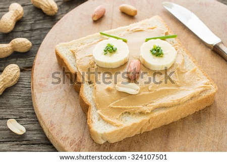 Slice of bread as funny face with peanut butter, banana and peanuts