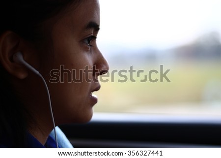 Silhouette edge  Asian girl sitting in the car listening to music from smartphone in-Thailand.