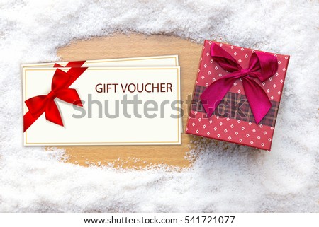 Red gift box with blank gift voucher cards top view on wood and ice,commerce on winter holidays concept