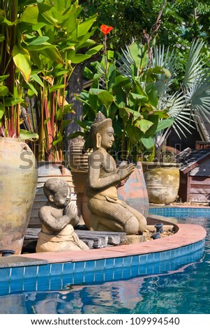 Stone Buddhist statues by the pool . Thailand .