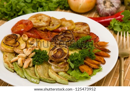 Baked vegetables: potato, zucchini, tomato, carrot, apple, onion on plate. Vegetarian food