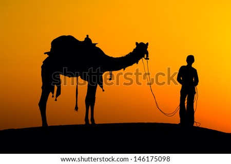 Rajasthan village. Silhouette of a man and camel at sunset in the desert, Jaisalmer - India