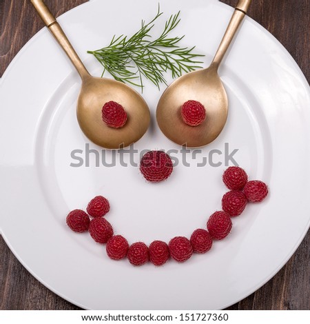 Fun food for kids - face on a plate of raspberries