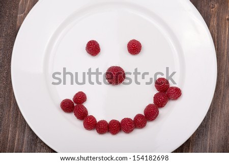 Fun food for kids - face on a plate of raspberries