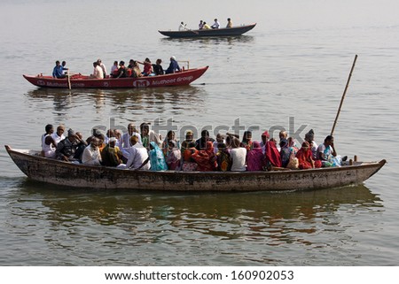 VARANASI, INDIA - DECEMBER 2: A lot of people sit on the crowded boats to cross the Ganges River on December 2, 2012 in Varanasi, India. The most holy river of India and Hindu culture.