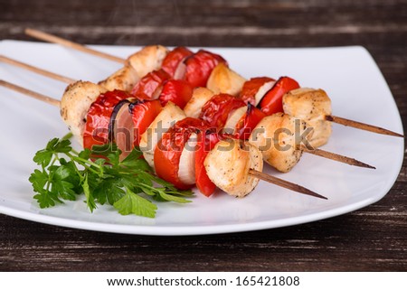 Tasty grilled meat and vegetables on skewer on plate