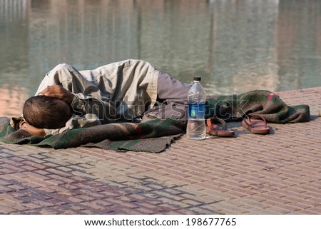 HARIDWAR, INDIA - NOV 8: An unidentified homeless man sleeps on the sidewalk near the River Ganges on November 8, 2012 in Haridwar, India. Poor Indians flock to Haridwar for charity.
