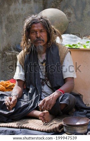 RISHIKESH, INDIA - OCTOBER 21, 2012 : Unidentified poor man sits on the ghat along the Ganges river. Poor Indians flock to Rishikesh for charity.