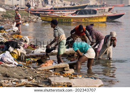 VARANASI, INDIA - DECEMBER 1, 2012: Unidentified Indian people wash clothes in Ganga river in Varanasi, India. For many dwellers of Varanasi the Ganga is only way to wash clothes.