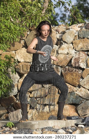 Young woman yoga doing shamanic dance on a nature background