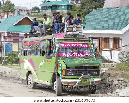 SRINAGAR, INDIA - JUNE 07, 2015: Local bus in indian inexpensive bus service. Local residents ride on the roof of the bus