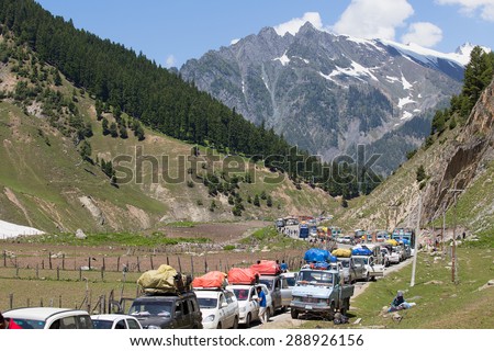 SRINAGAR, INDIA - JUNE 12, 2015: Cars with passengers stuck at the pass on the way Srinagar - Leh, Indian Himalayas. Cars are waiting for the bulldozer will clear the mountain road from a landslide