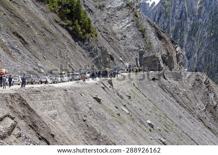 SRINAGAR, INDIA - JUNE 12, 2015: Cars with passengers stuck at the pass on the way Srinagar - Leh, Indian Himalayas. Cars are waiting for the bulldozer will clear the mountain road from a landslide