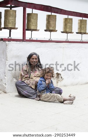 LEH, INDIA - JUNE 24, 2015: Unknown beggar woman with a child begging near a Buddhist temple in Leh, Ladakh. Poverty is a major issue in India