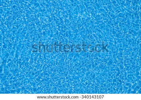 Water ripples on blue tiled swimming pool background. View from above.