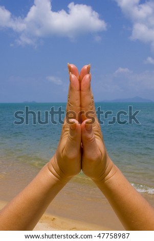 Hands clasped in religious prayer against sky background