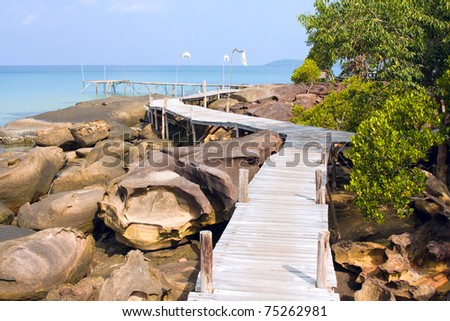 Scenic sea coastline of the Ko Kood island in Thailand with wooden path along the rocky shore