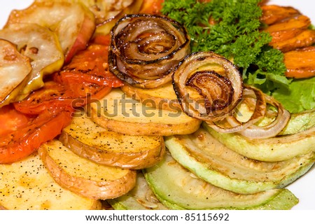 Baked vegetables: potato, zucchini, tomato, apple, onion on plate. Vegetarian food