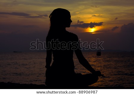 Healthy woman doing yoga outdoor, sunset over sea