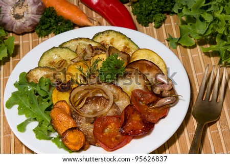 Baked vegetables: potato, zucchini, tomato, carrot, apple, onion on plate. Vegetarian food