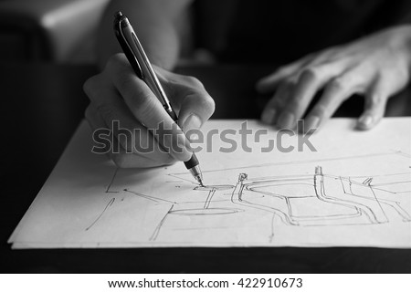 The hand of the designer with a pen, designing and sketching a furniture product in monochrome