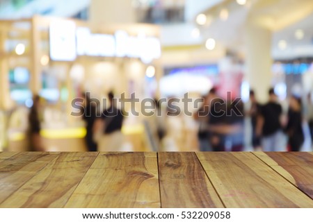 blurred image wood table and  people walking in shopping centre