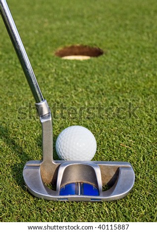 Closeup view from behind a putt on a golf green, as the golfer lines up a short putt. Short depth of field with focus on the golf ball.