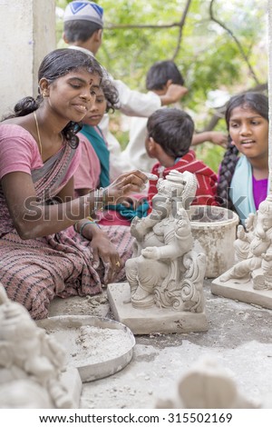 ANANTAPUR,INDIA-CIRCA 2014 - Ganesha idol being given finishing touches by an unidentified women as the kids around her look on in Anantapur before Ganesh Chaturthi.
