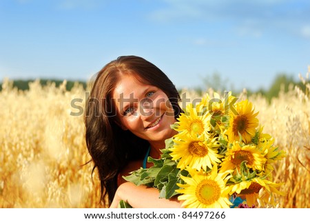 Portrait of young woman with sunflowers in wheat field