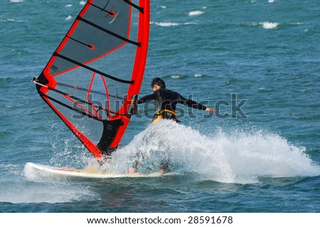 water sports: windsurfer with bright colored sail on taiwan blue water