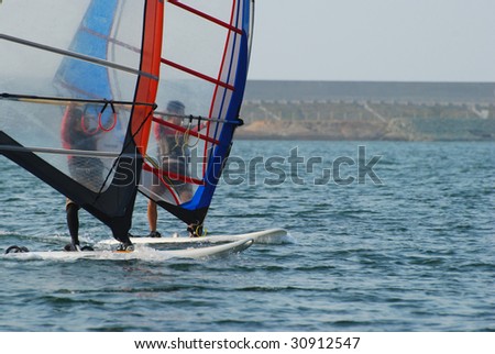 water sports: windsurfer with bright colored sail on taiwan blue water