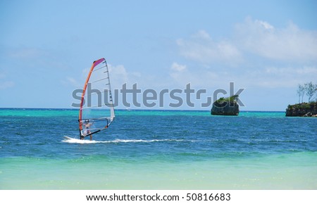 water sports: windsurfer with bright colored sail in Philippines blue water