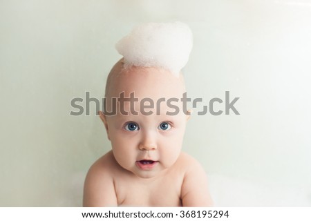 Baby with soap foam or shampoo on his head
