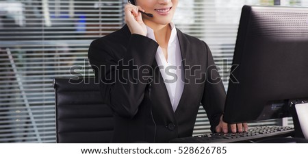 a happy executive wearing suit calling customer service on the phone and sitting on a desk in the office