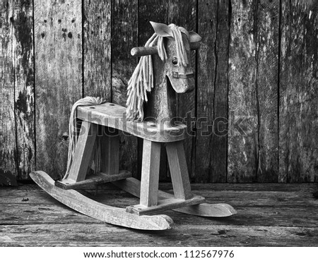 Antique rocking horse on a rustic country backdrop, desaturated..