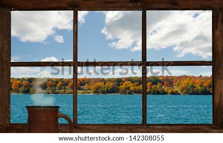 Autumn lakefront view with a cup of steaming coffee, as seen through the cottage window. Part of a series.